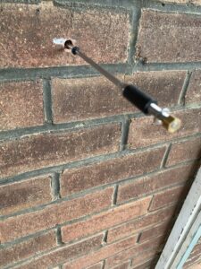 Neoprene replacement wall tie being installed into cavity brickwork in Deal